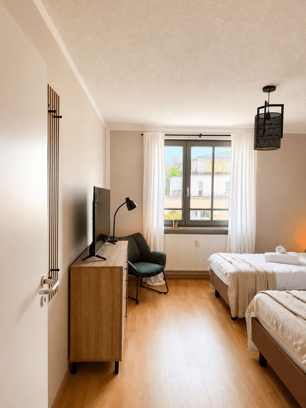 Zweites Schlafzimmer mit Sideboard, TV und Sessel – Trenta Living Wohnung in Dresden